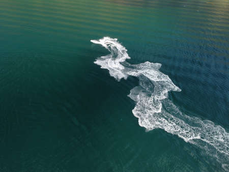 People are playing a jet ski in the sea, leaving abstract white footprints on the water. Aerial top view. Amazing nature background. Water color are beautifully vibrant. Fresh freedom. Adventure day.の写真素材