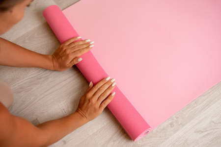 Young woman with long hair, fitness instructor in beige sportswear, preparing for stretching and pilates on yoga mat in the gym. Female fitness yoga concept. Healthy lifestyle harmony and meditation.の写真素材