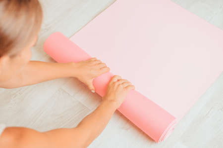 Young woman with long hair, fitness instructor in beige sportswear, preparing for stretching and pilates on yoga mat in the gym. Female fitness yoga concept. Healthy lifestyle harmony and meditation.の写真素材