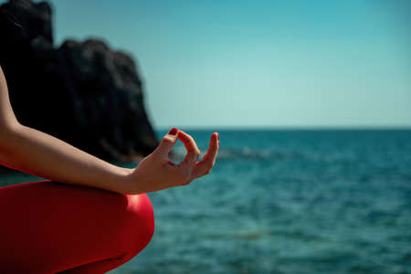 Young woman with long hair, fitness instructor in Sportswear Leggings and Tops, stretching before pilates, on a yoga mat near the sea on a sunny day, female fitness yoga routine conceptの写真素材
