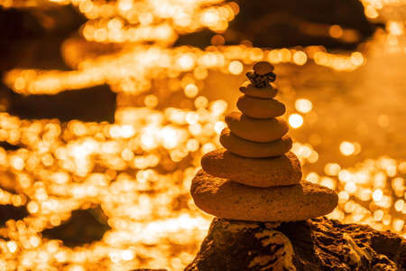 Pyramid stones on the seashore on a sunny day on the blue sea background. Happy holidays. Pebble...
