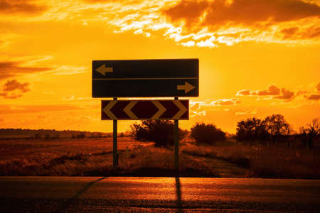 Empty blue direction crossroads road signs representing oportunities with red burning sunset...