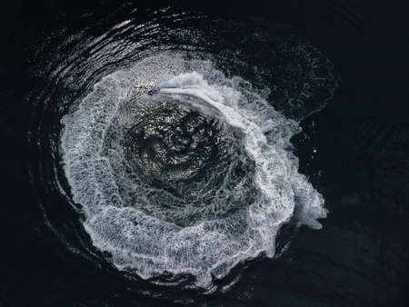 People are playing a jet ski in the sea, leaving abstract white footprints on the water. Aerial top view. Amazing nature background. Water color are beautifully vibrant. Fresh freedom. Adventure day.の写真素材