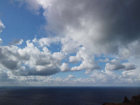 Abstract airy sky with moving plump clouds over the sea ocean. Small waves on clear water surface...