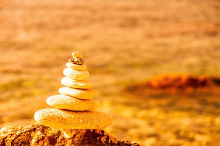 Pyramid stones on the seashore on a sunny day on the blue sea background. Happy holidays. Pebble beach, calm sea, travel destination. Concept of happy vacation on the sea, meditation, spa, calmness.の写真素材