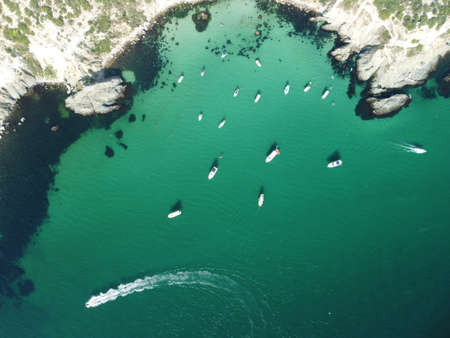 Aerial panoramic view of seascape with crystal clear azure sea and rocky shores. Yachts in a beautiful lagoon on backdrop of rocks. The concept of an ideal destination for summer travel and vacation.の写真素材