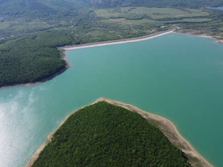 Aerial view on water reservoir at mountain valley covered with green spring forest. Beautiful view...
