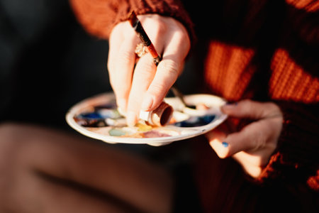 A womans hands mixing paints on a palette board. Preparing to paint a picture. Artistic tools. The creative process.の写真素材