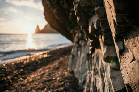 Dramatic Seascape over the beach during sunset, with rocky volcanic cliff is lit by the warm sunset. Clear sky no clouds. Nobody. The concept of calmness silence and unity with nature. Selective focusの写真素材