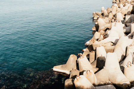 Coast breakwaters protecting from large waves with sea water background. The seashore is reinforced with concrete tetrapods.の写真素材