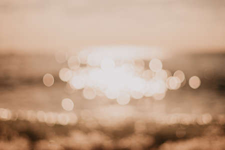 Abstract nature summer ocean sunset sea background. Small waves on water surface in motion blur with bokeh lights from sunrise. Holiday, vacation and recreational background concept.の写真素材