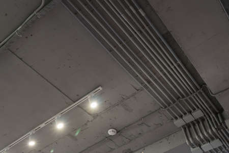 Abstract loft interior of concrete grey ceiling with air ventilation and security camera. Interior architecture and ceiling design of industrial loft building decorated with modern lampsの写真素材