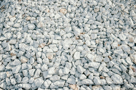 Granite stones behind a metal grate for strengthening the slope. Stones behind the wire. grey texture. construction.の写真素材