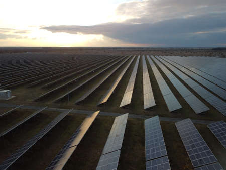 Aerial top view of a solar panels power plant. Photovoltaic solar panels at sunrise and sunset in countryside from above. Modern technology, climate care, earth saving, renewable energy concept.の写真素材