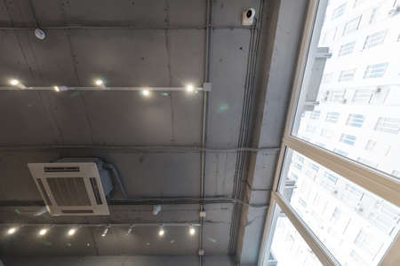 Abstract loft interior of concrete grey ceiling with air ventilation and security camera. Interior...