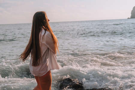 Selective focus. Happy carefree sensual woman with long hair in black swimwear posing at sunset...