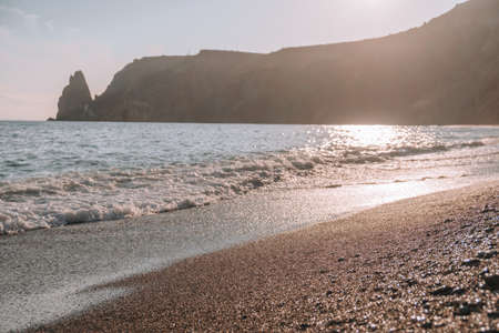 Selective focus. Happy carefree sensual woman with long hair in black swimwear posing at sunset beach. Silhouette of young beautiful playful positive woman outdoor. Summer vacation and trip conceptの写真素材