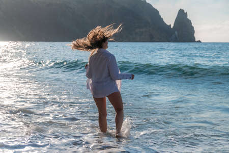 Selective focus. Happy carefree sensual woman with long hair in black swimwear posing at sunset...