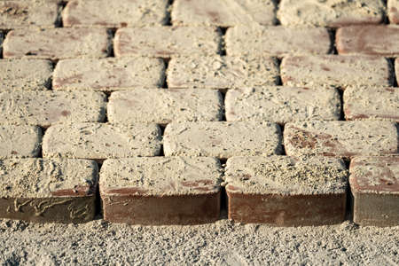 Brown concrete permeable flooring assembled on a substrate of sand. Abstract photo of bricks in the sunlightの写真素材