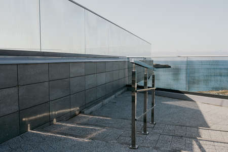 Glass fence in the seaside park. a popular viewpoint, admiring the natural beauty of the sunset. An observation deck with a figured fence and a lantern. City view.の写真素材
