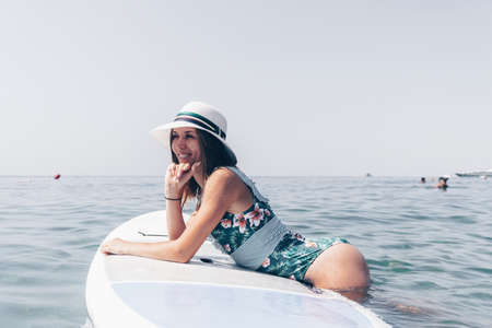 SUP Stand up paddle board. Young woman sailing on beautiful calm sea with crystal clear water. The concept of an summer holidays vacation travel, relax, active and healthy life in harmony with nature.の写真素材