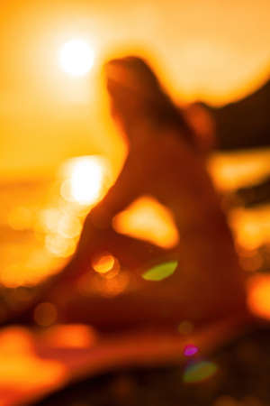 Abstract defocused silhoute of middle aged well looking woman with black hair doing Pilates with the...