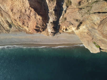Aerial view from above on calm azure sea and volcanic rocky shores. Small waves on water surface in motion blur. Nature summer ocean sea beach background. Nobody. Holiday, vacation and travel conceptの写真素材