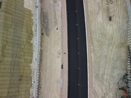 Workers reinforce the slope over the new road. Road construction in progress on slope nature canyon. Infrastructure development and logistics. Aerial drone shotの写真素材