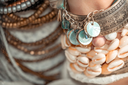 Close up of beautiful tribal boho style woman hands with lots of accessories. Boho style for fashionable look on resort. Middle aged well looking woman in white dress and boho style braclets.の写真素材