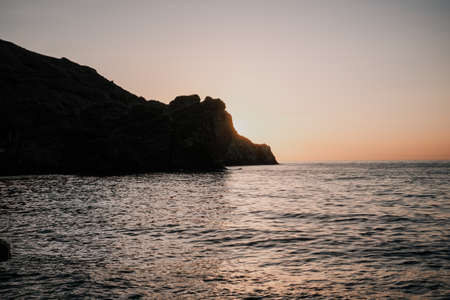 A red burning sunset over the sea with rocky volcanic cliff. Abstract nature summer or spring ocean...