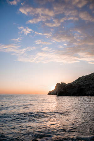 A red burning sunset over the sea with rocky volcanic cliff. Abstract nature summer or spring ocean...