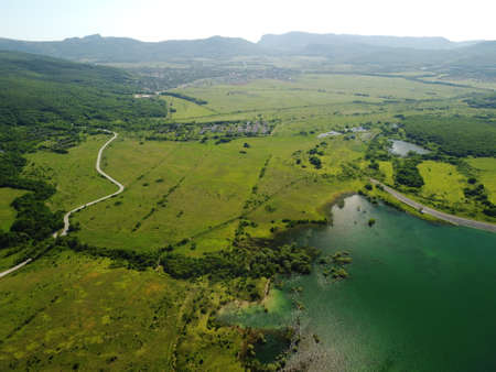 Aerial view on water reservoir at mountain valley covered with green spring forest. Beautiful view from above on smooth blue surface of mountain lake among highlands. Drone point of view. Nobodyの写真素材