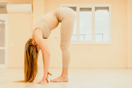 Young sporty woman, fitness instructor in sportswear doing stretching and pilates on yoga mat in the studio with mirror. Female fitness yoga routine concept. Healthy lifestyle and harmony.の写真素材
