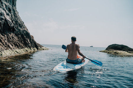 Side view foto of a man swiming and relaxing on the sup board. Sportive man in the sea on the Stand Up Paddle Board SUP. The concept of an active and healthy life in harmony with nature.の写真素材