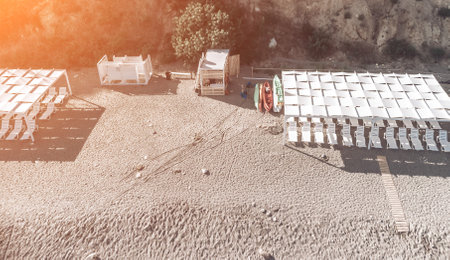 Empty sun loungers under a canopy on the beach. The beach area is empty. No people. White plastic sunbeds under the sun shade. The holiday season ends. Holiday season begins. Waiting for tourists.の写真素材