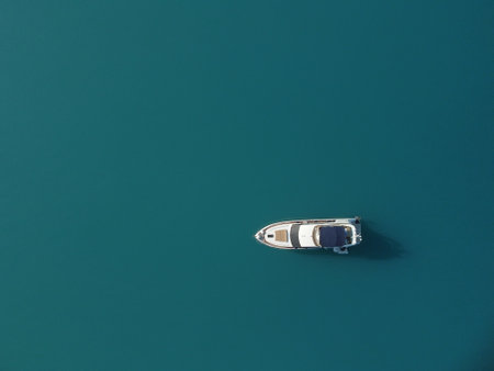 Aerial yacht on calm sea. Luxury cruise trip. View from above of white boat on deep blue water. Aerial top down view of rich yacht sailing sea. Summer journey on luxury ship.の写真素材