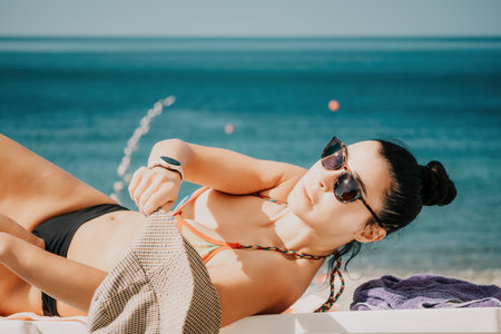 Woman in rainbow bikini. Happy tanned well looking middle aged woman in rainbow swimsuit at seaside, blue sea water in background. Holiday, vacation and recreational concept.の写真素材