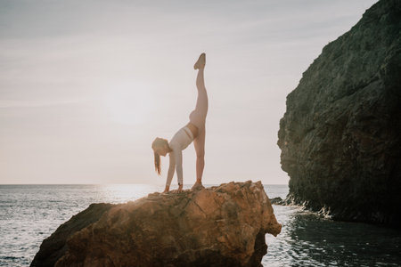 Young woman with black hair, fitness instructor in pink leggings and tops doing stretching and pilates on volcanic rocks near the sea on sunset. Female fitness yoga routine concept. Healthy lifestyle.の写真素材