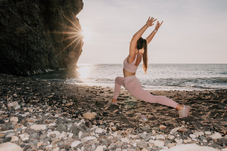 Young woman with black hair, fitness instructor in pink leggings and tops doing stretching and pilates on volcanic rocks near the sea on sunset. Female fitness yoga routine concept. Healthy lifestyle.の写真素材