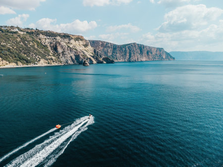 Happy people swim on air mattress behind a high speed water bike. Tourists ride on inflatable...