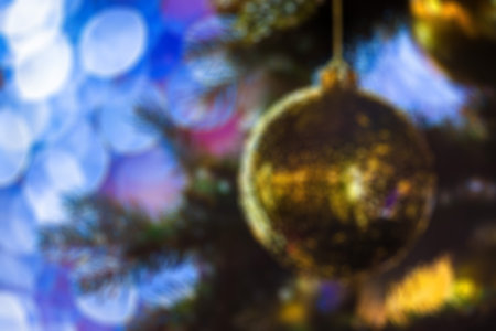 Closeup of Festively Decorated Outdoor Christmas tree with bright gold ball on blurred sparkling fairy background. Defocused garland lights, Bokeh effect. Christmas and New Year conceptの写真素材