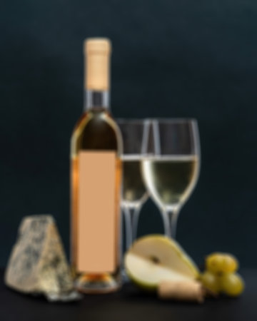 Abstract defocused blured background composition with glass and bottle of white wine with blue mold cheese, pear and grapes on grey background. copy spaceの写真素材