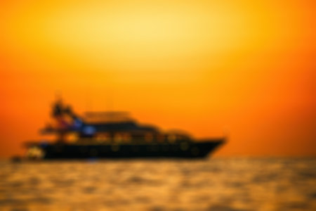 Golden romantic sunset on private modern luxury yacht anchored at sea - luxury holidays and travel concept. A red burning sunset over the sea with the silhouette of a fashionable yacht.の写真素材