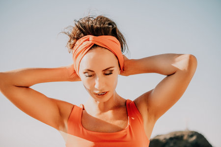 Woman sea yoga. Selective focus. Young beautiful caucasian woman in a red suit practicing yoga on the beach at sunrise near the sea. Yoga. Healthy lifestyle. Meditation concept.の写真素材