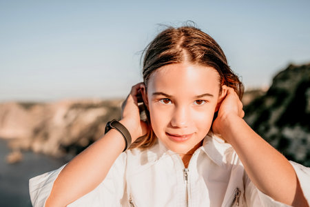Adorable teenage girl outdoors enjoying sunset at beach on summer day. Close up portrait of smiling...