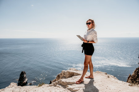 Digital nomad, Business woman working on tablet pc pad computer by the sea. Pretty lady with tablet pc on the sea, makes a business transaction online from distance. Freelance, remote work on vacationの写真素材