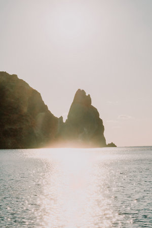 A red burning sunset over the sea with rocky volcanic cliff. Abstract nature summer ocean sea...