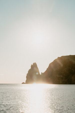 A red burning sunset over the sea with rocky volcanic cliff. Abstract nature summer ocean sea...