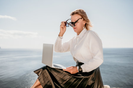 Digital nomad, Business woman working on laptop by the sea. Pretty lady typing on computer by the...