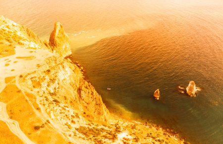 Aerial view from above on calm azure sea and volcanic rocky shores. Small waves on water surface in motion blur. Nature summer ocean sea beach background. Nobody. Holiday, vacation and travel conceptの写真素材